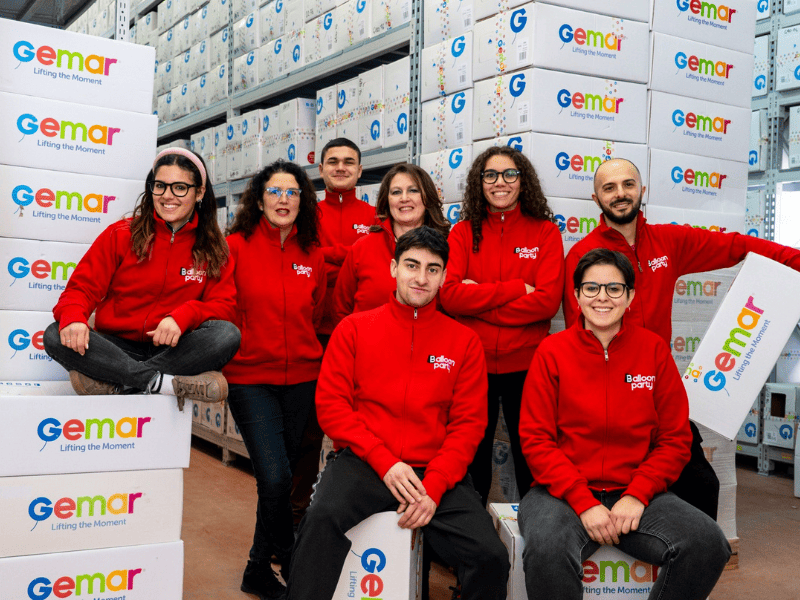parte dello staff di balloon party in felpa rossa che sorride con pacchi gemar in mano