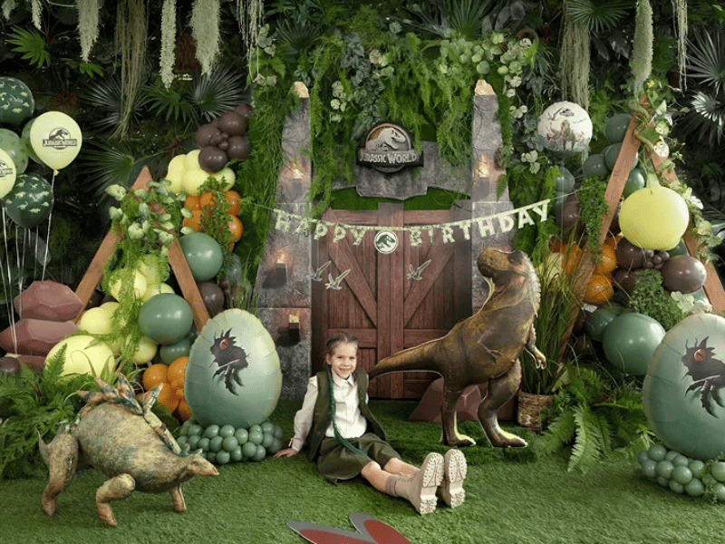Festa a tema dinosauri Jurassic World con palloncini verdi e allestimento scenografico