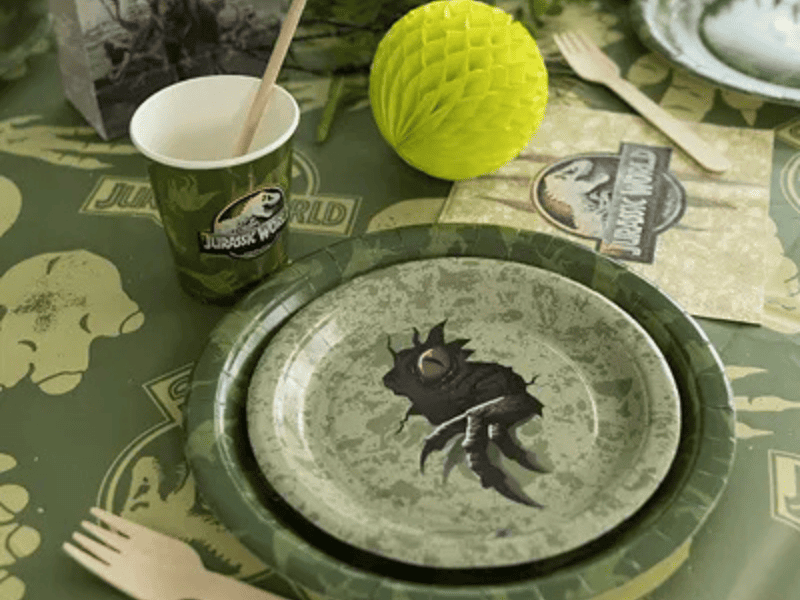 Tavolo festa a tema dinosauri con piatti, bicchieri e decorazioni Jurassic World