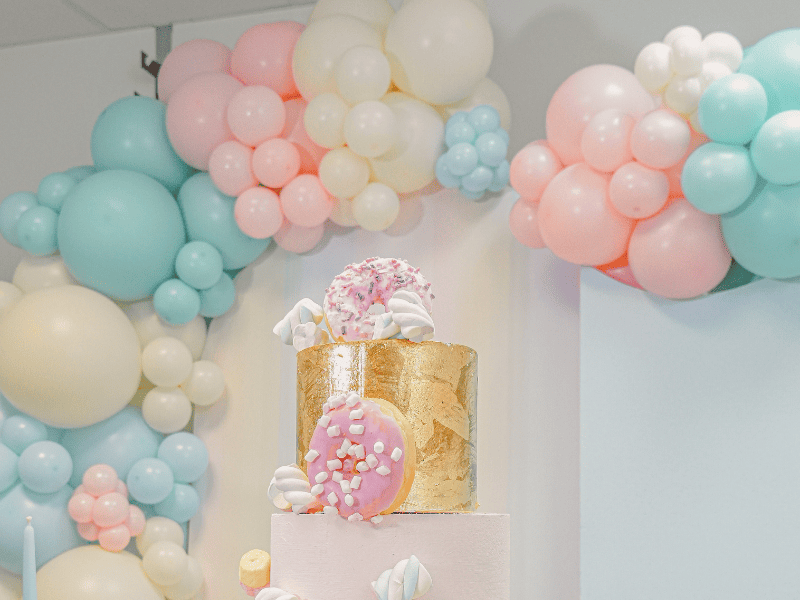 palloncini gemar marshmallow sullo sfondo color lino, azzurro polvere, rosa polvere, tiffany e burro. In primo mpiano dei marshmallow e una ciambella rosa