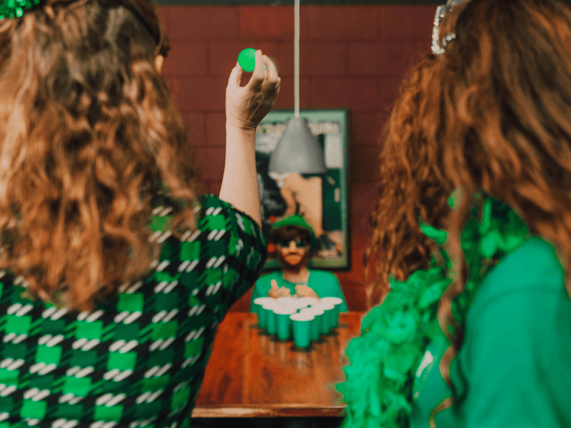 Gioco beer pong verde per Festa di San Patrizio con outfit a tema Irlanda e atmosfera pub irlandese