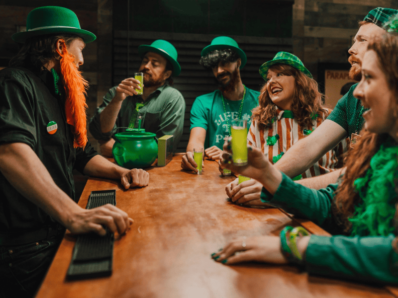 Festa di San Patrizio in pub con amici vestiti di verde che brindano con drink verdi, atmosfera irlandese St. Patrick’s Day
