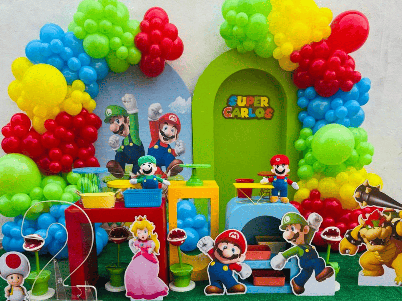 allestimento festa super mario bambini con palloncini rossi blu gialli e decorazioni del regno dei funghi